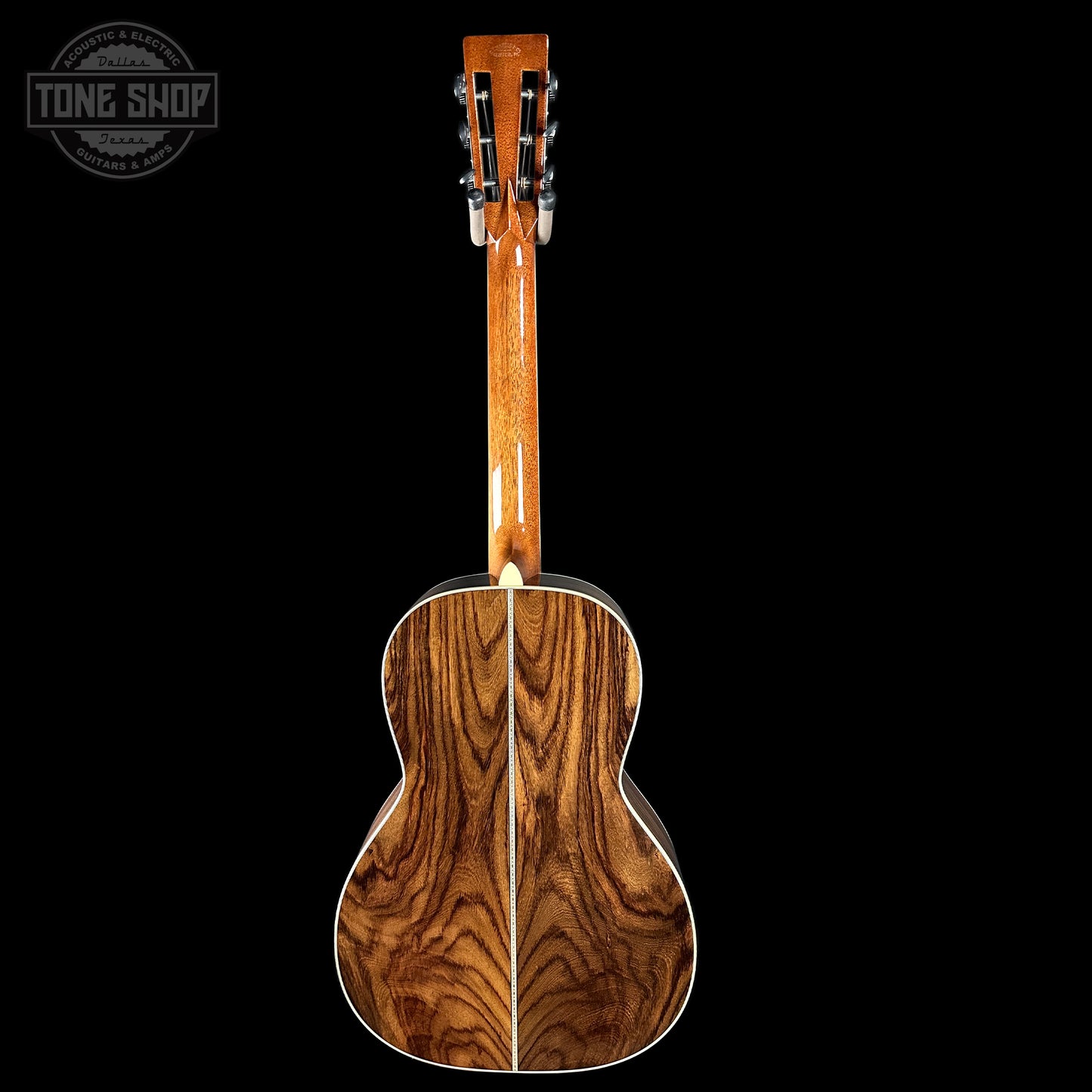 Back view of a wooden acoustic guitar with 'Tone Shop' logo.