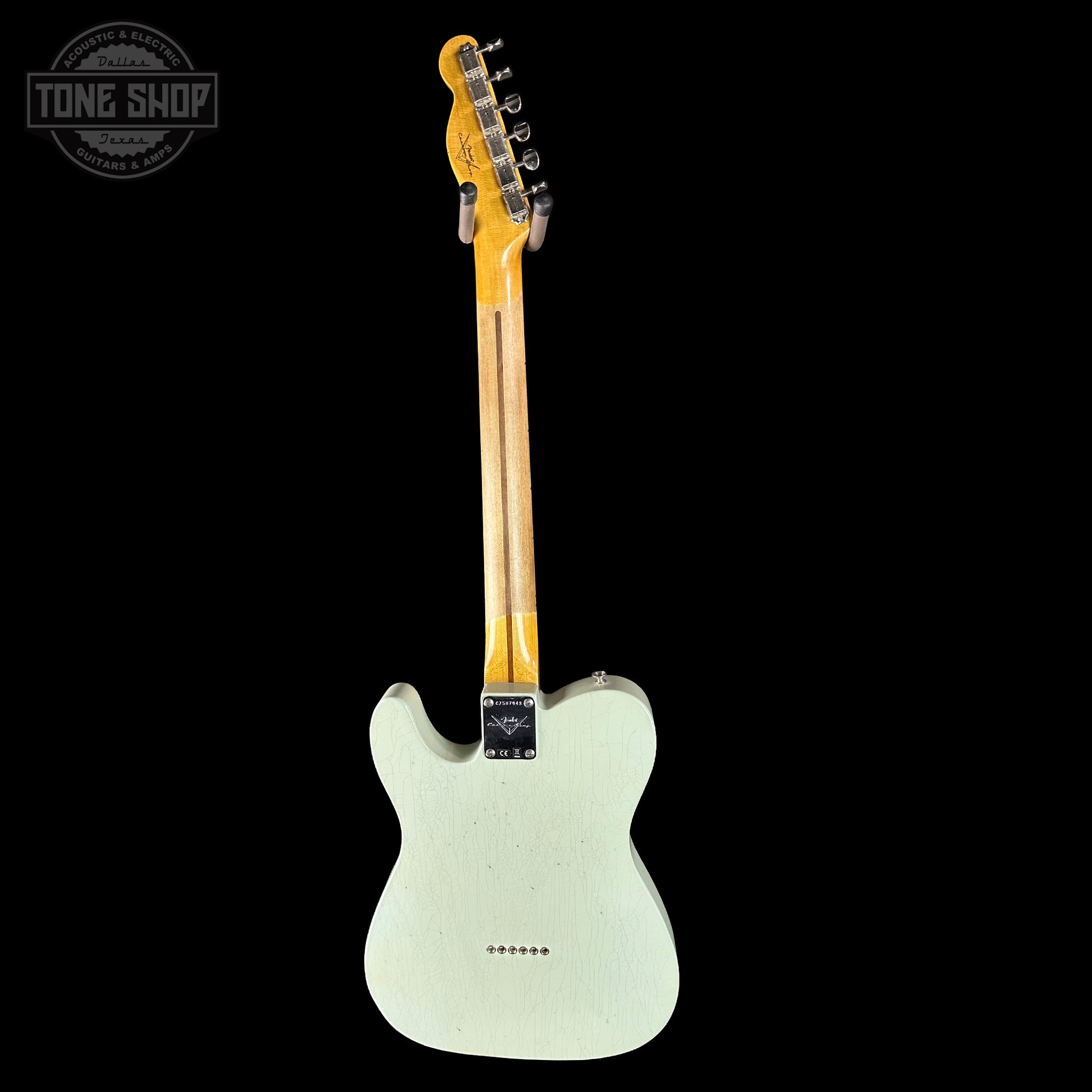 Electric guitar with a light-colored body and dark neck on a black background, featuring 'Tone Shop' logo.