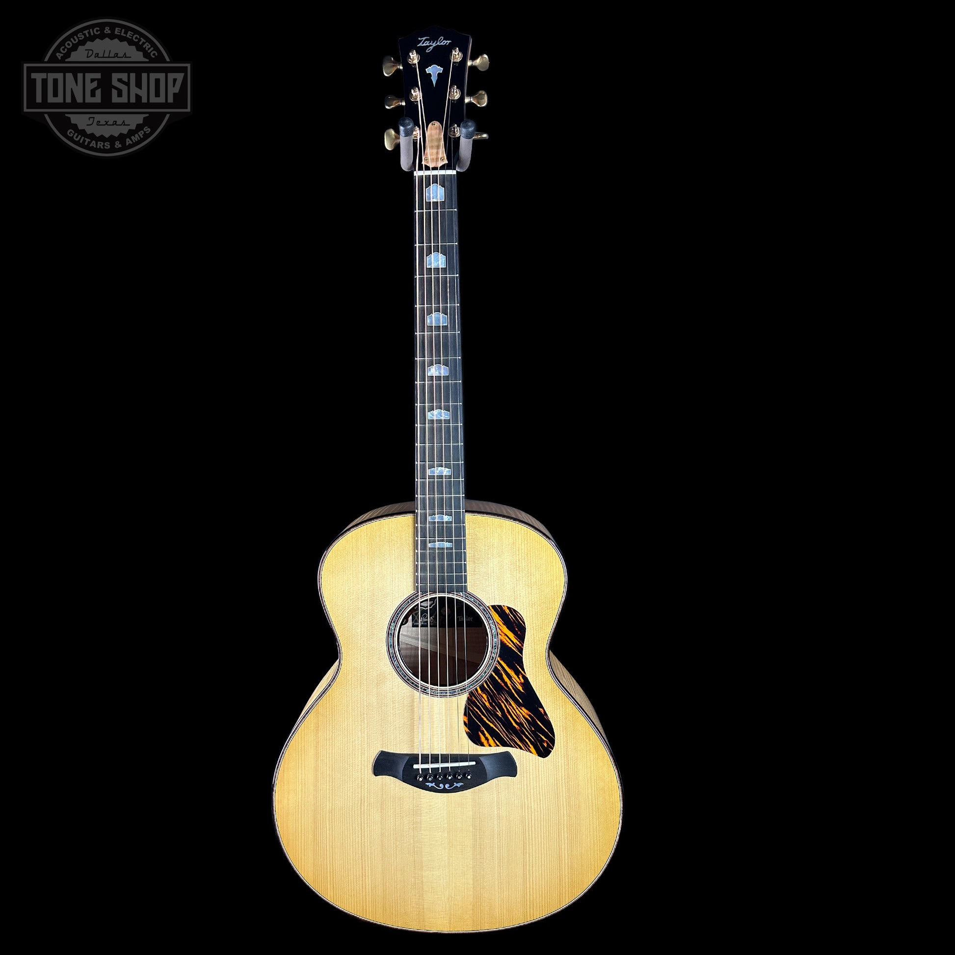 Acoustic guitar with a flame maple top on a black background, featuring the Tone Shop logo.