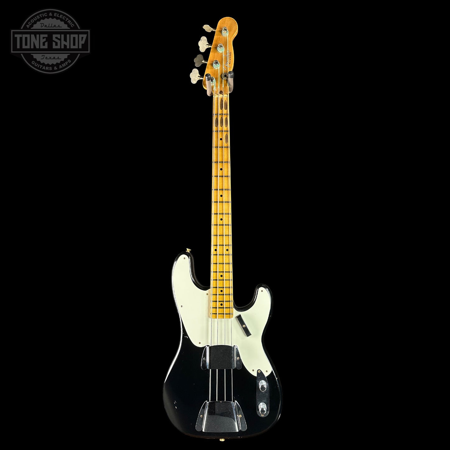 Electric bass guitar with a black body and on a black background, featuring the Tone Shop logo.