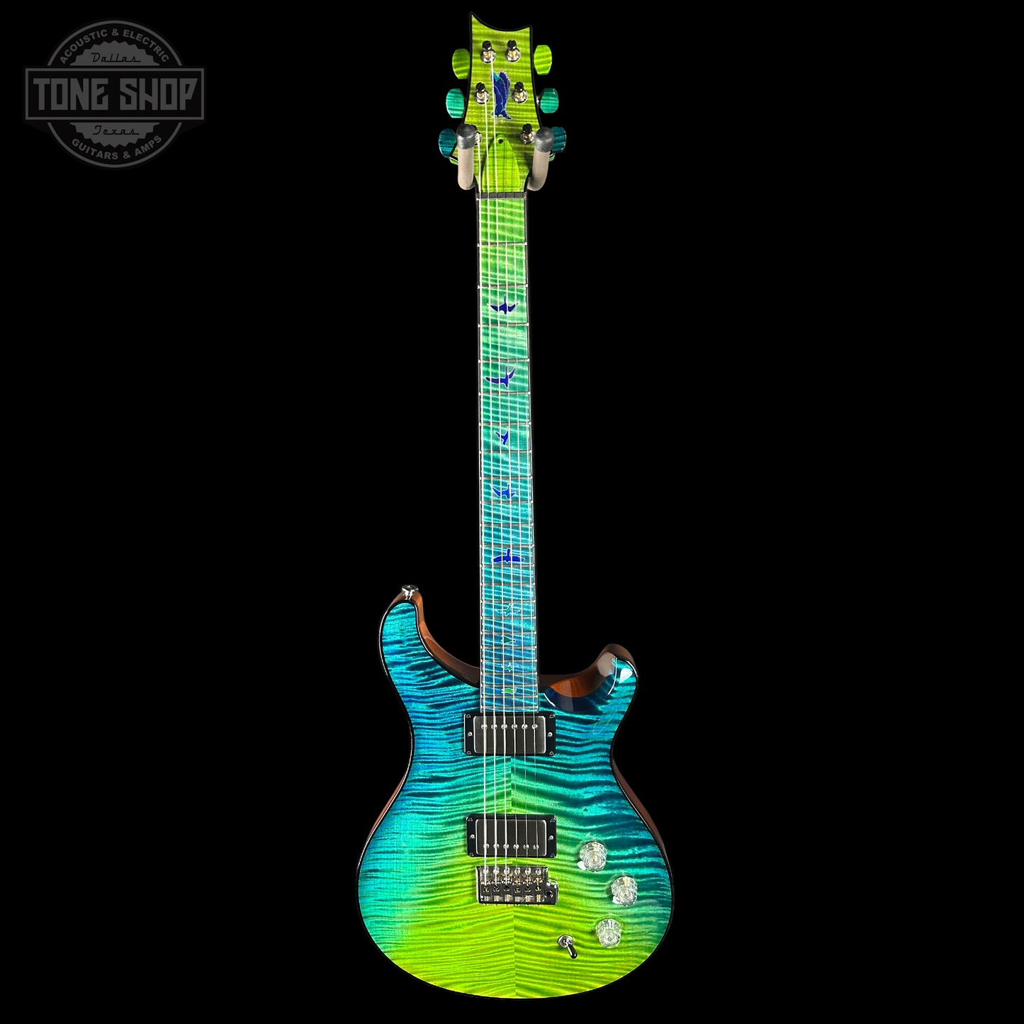 Colorful electric guitar with a gradient design on a black background, featuring the Tone Shop logo.