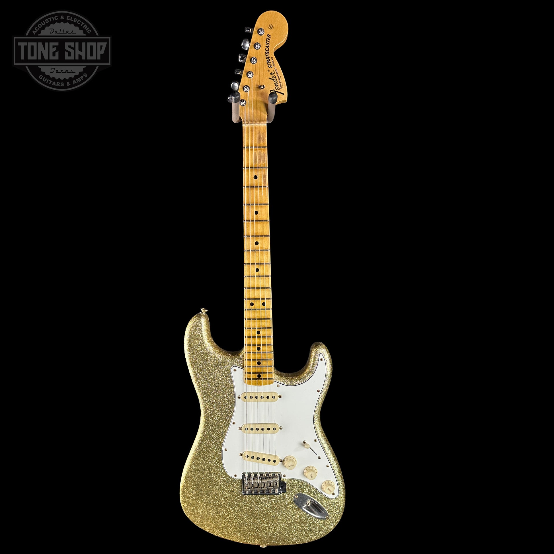 Gold glitter electric guitar with a white pickguard on a black background, featuring 'Tone Shop' logo.