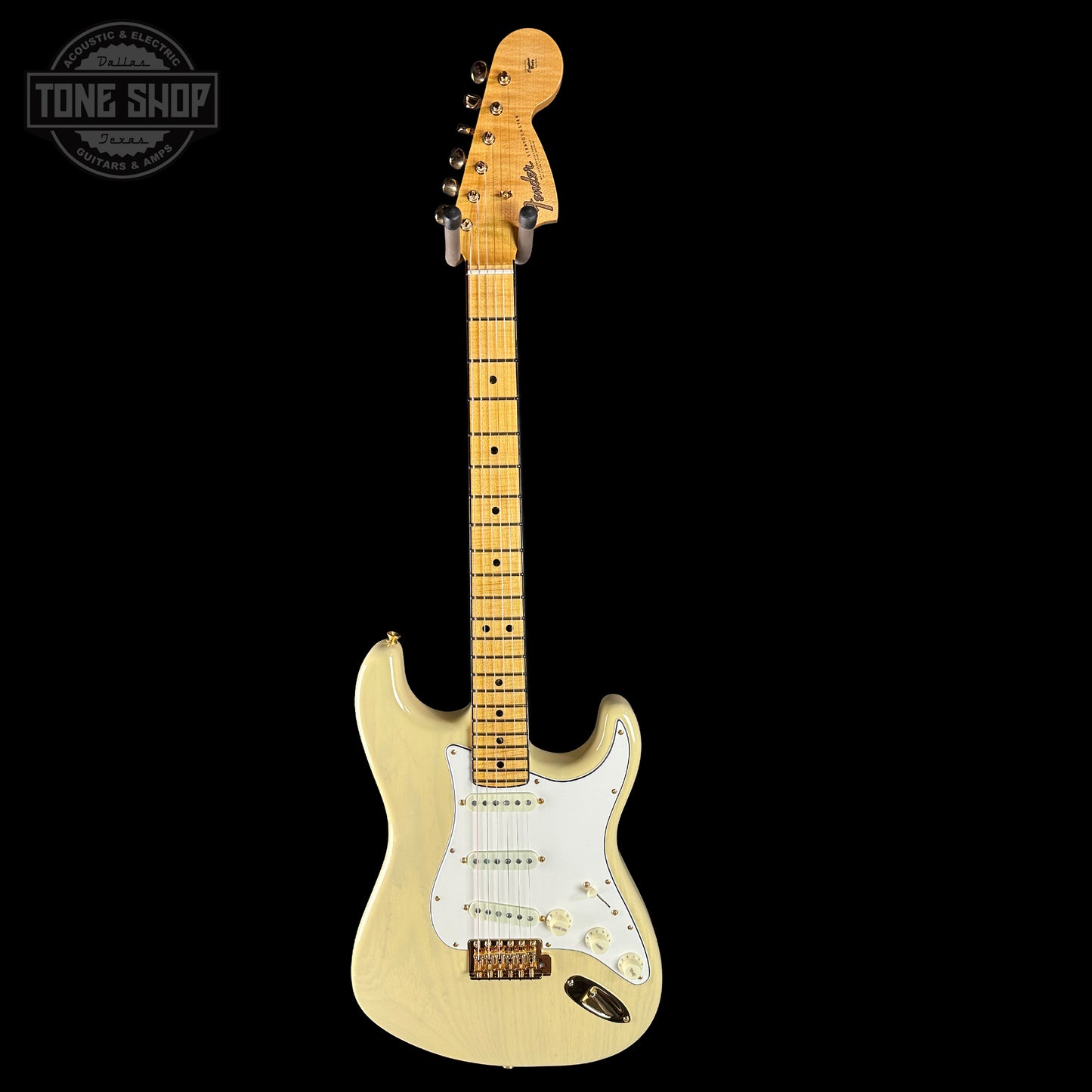 Beige electric guitar with a wooden neck on a black background, featuring 'Tone Shop' logo.