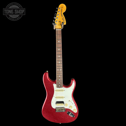 Red electric guitar with a white pickguard on a black background, featuring the Tone Shop logo.