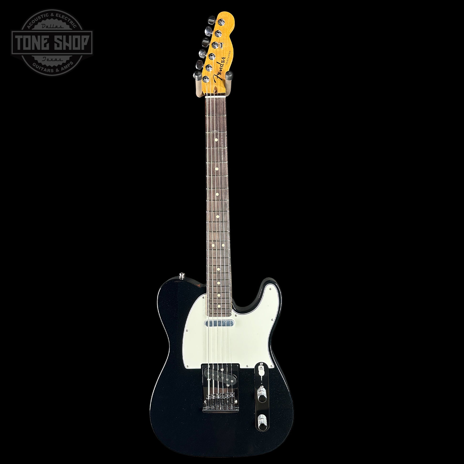 Electric guitar with a black body and white pickguard on a black background, featuring the Tone Shop logo.