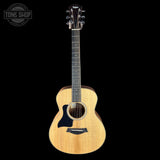 Acoustic guitar with a visible Taylor logo on a black background