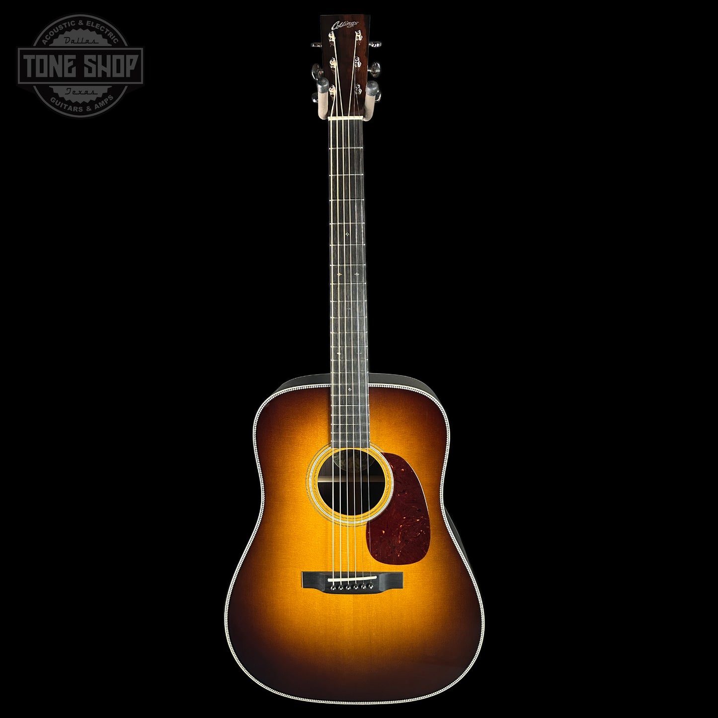 Acoustic guitar with a sunburst finish on a black background, featuring the Tone Shop logo.
