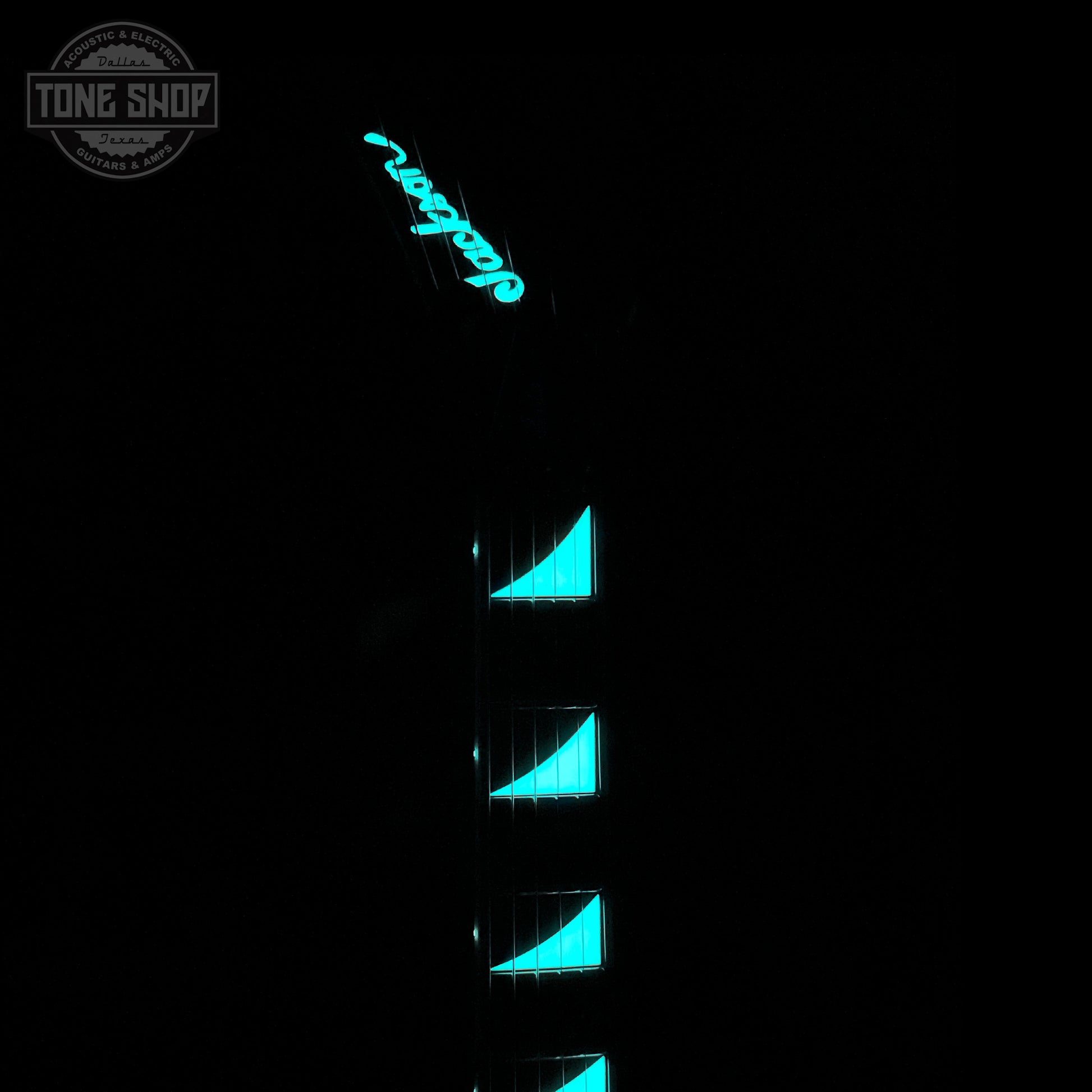 Guitar with blue glowing inlays on a black background, featuring the Tone Shop logo.