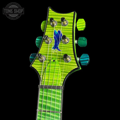 Close-up of a green electric guitar neck with headstock on a black background, featuring the Tone Shop logo.