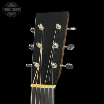 Close-up of a guitar headstock with tuning pegs on a black background, featuring the Tone Shop logo.