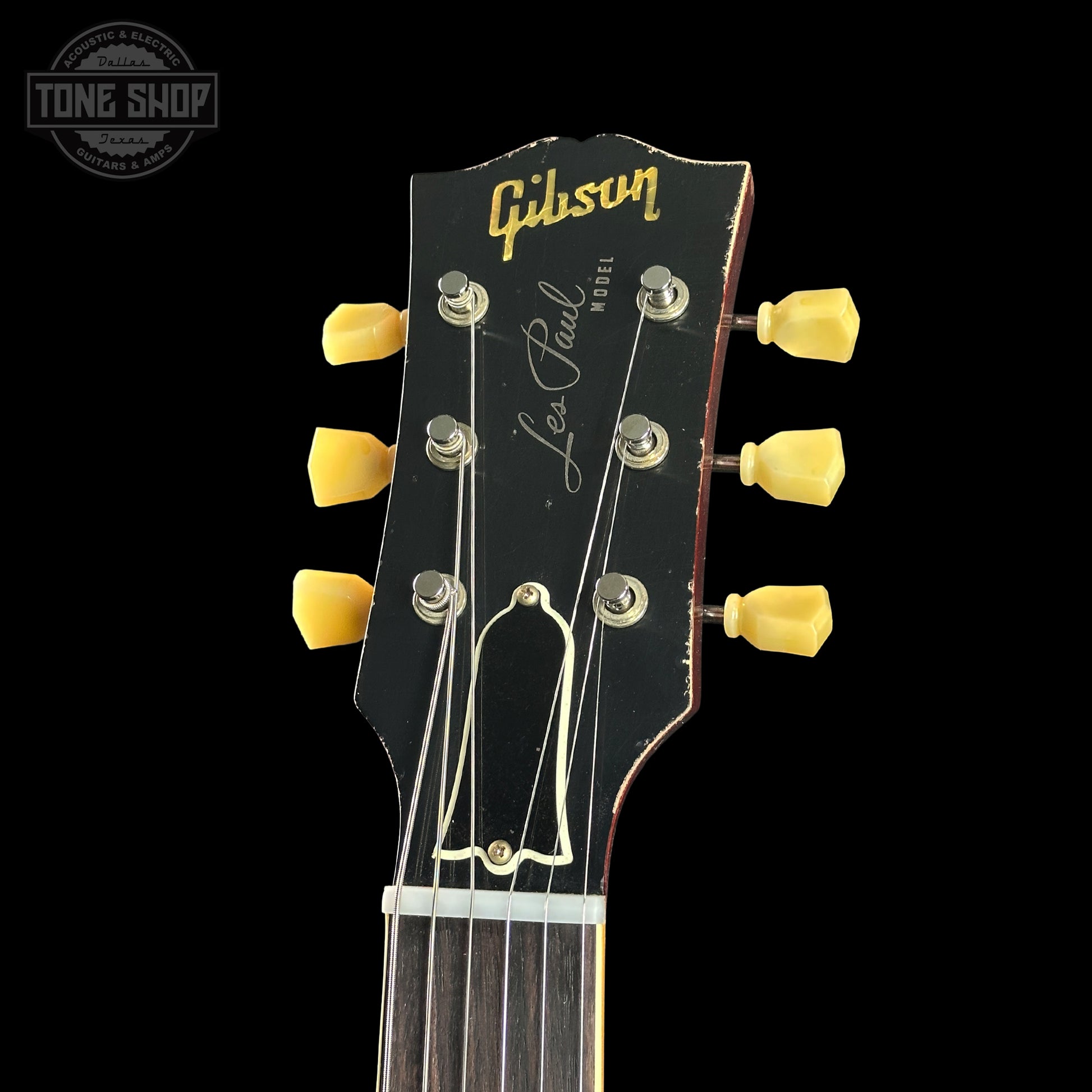 Gibson Les Paul guitar headstock with yellow tuning pegs on a black background