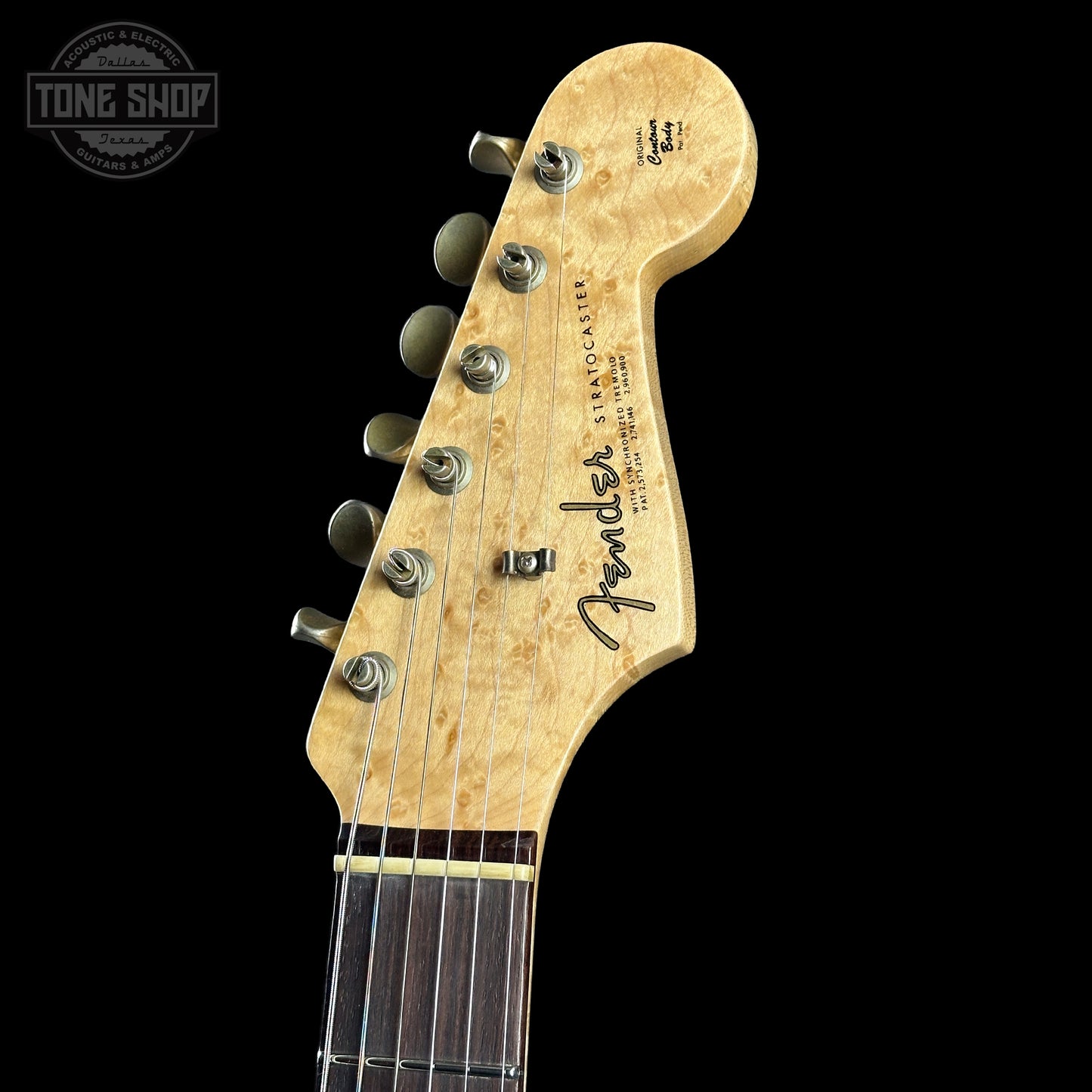 Close-up of a Fender Stratocaster guitar headstock with 'Tone Shop' logo in the corner.