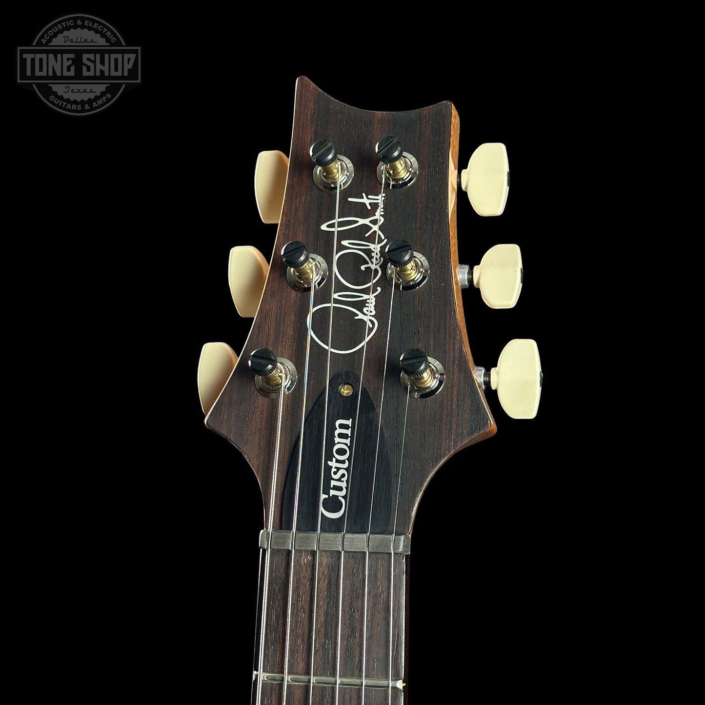Guitar headstock with 'Custom' branding on a black background