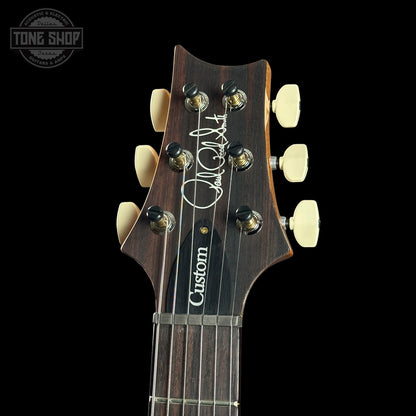 Guitar headstock with 'Custom' branding on a black background