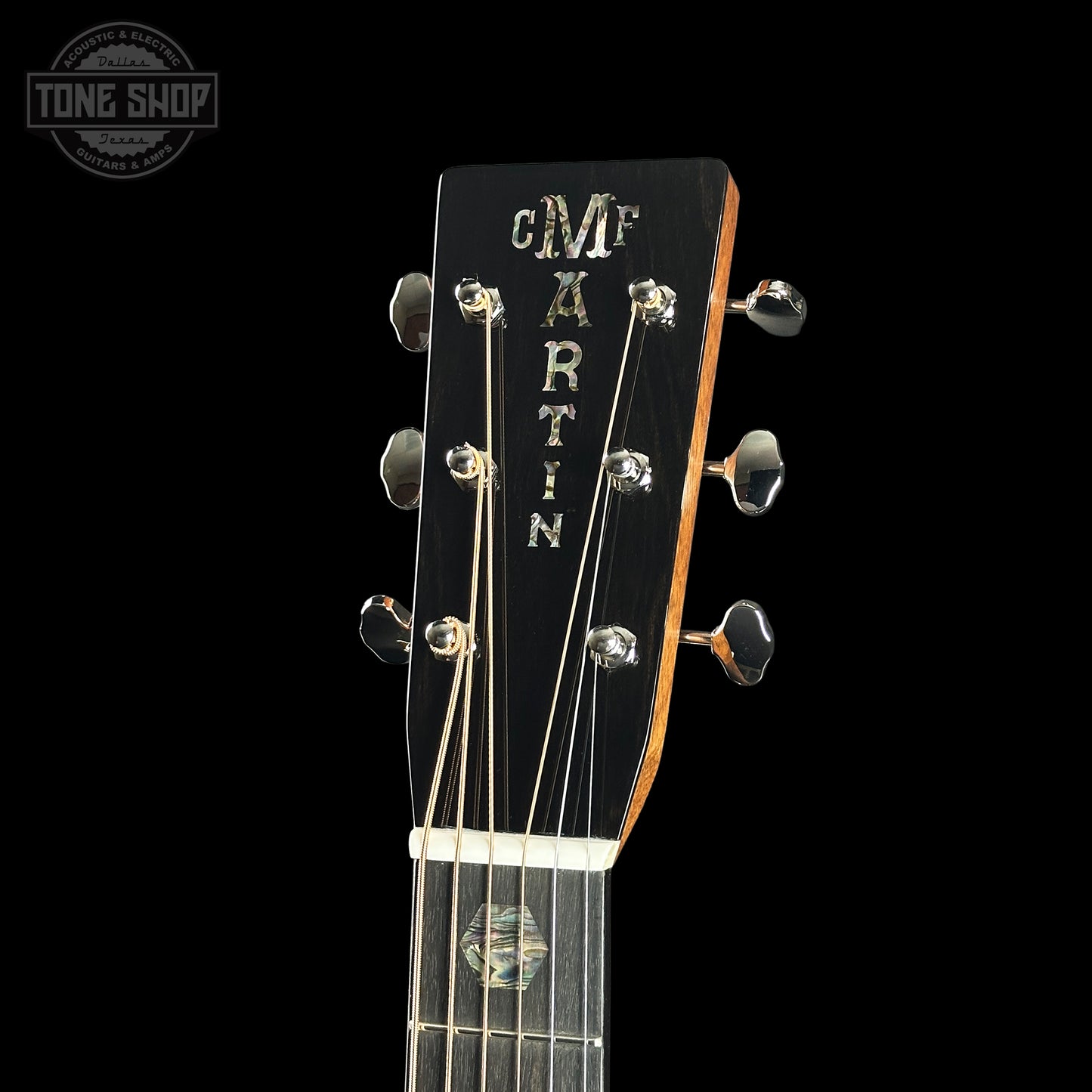 Close-up of a Martin guitar headstock with brand name on a black background