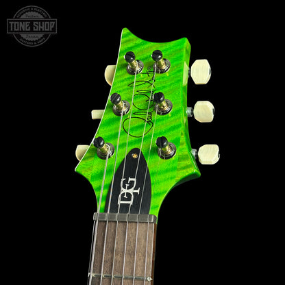Close-up of a green guitar headstock with tuning pegs on a black background, featuring the Tone Shop logo.