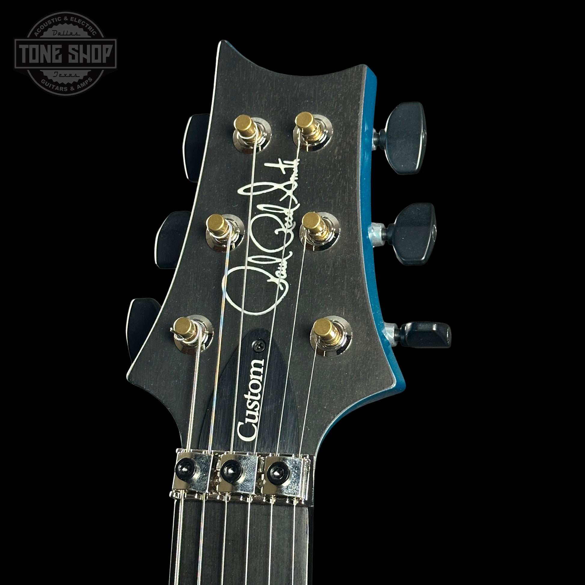 Guitar headstock with 'Custom' branding on a black background