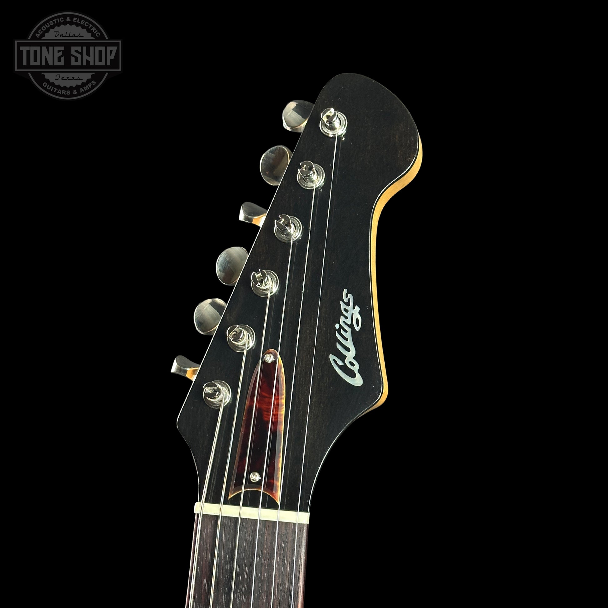 Close-up of a guitar headstock with 'Collings' logo on a black background