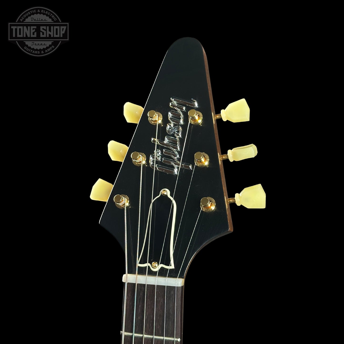 Close-up of a guitar headstock with 'Gibson' branding on a black background.