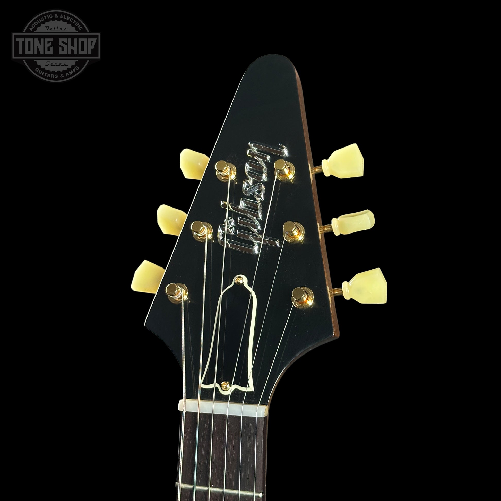 Close-up of a guitar headstock with 'Gibson' branding on a black background.
