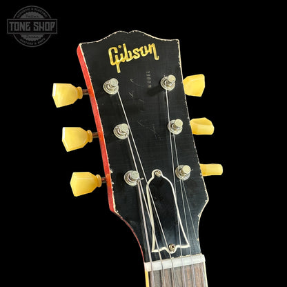 Gibson guitar headstock with yellow tuning pegs on a black background