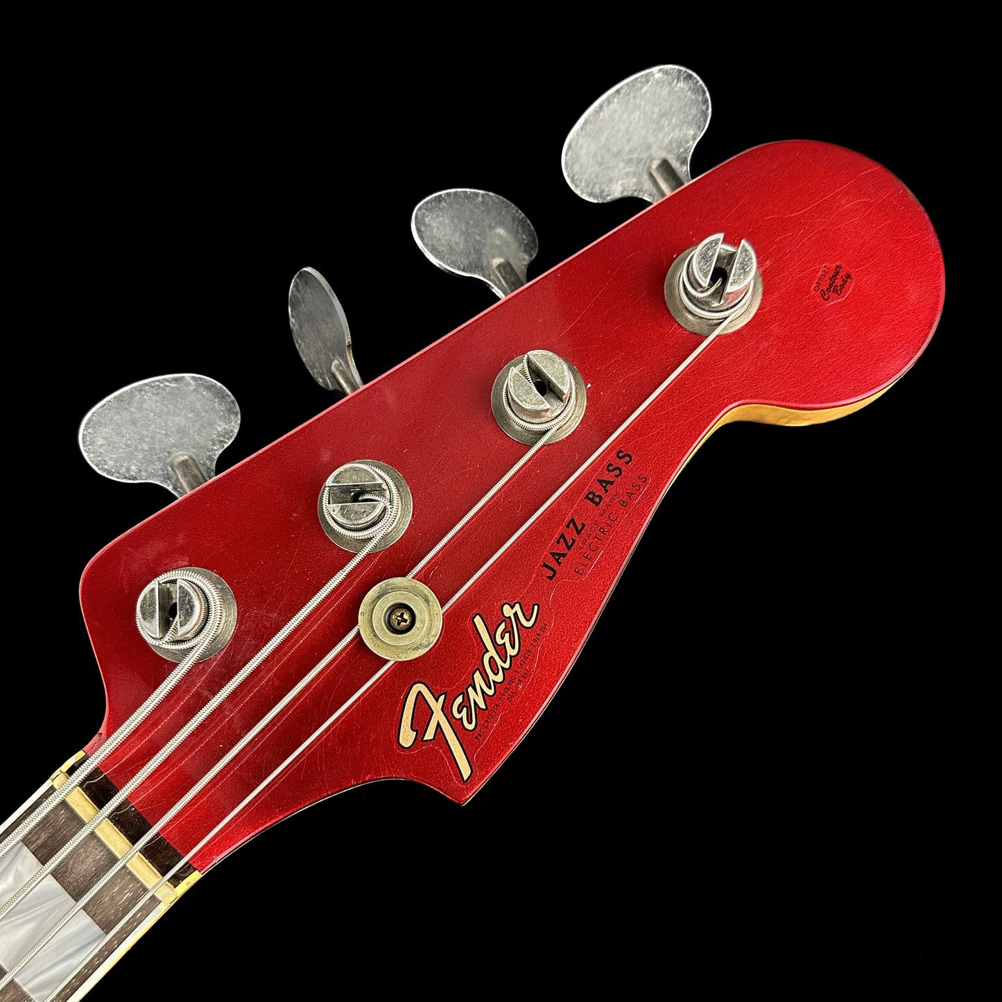 Closeup of Fender Custom Shop Limited P Jazz Bass Journeyman Aged Candy Apple Red headstock.