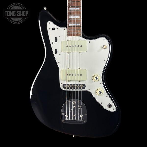 Black electric guitar with a white pickguard on a black background, featuring 'Tone Shop' branding.
