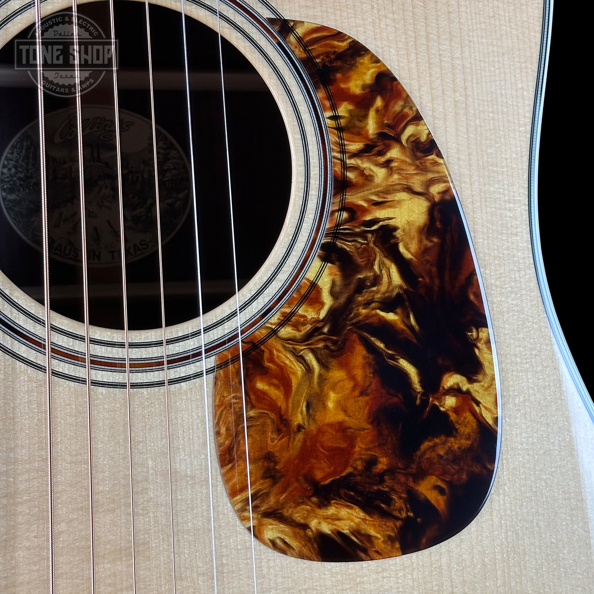 Close-up of a guitar's soundhole with a tortoiseshell pattern on a beige background.