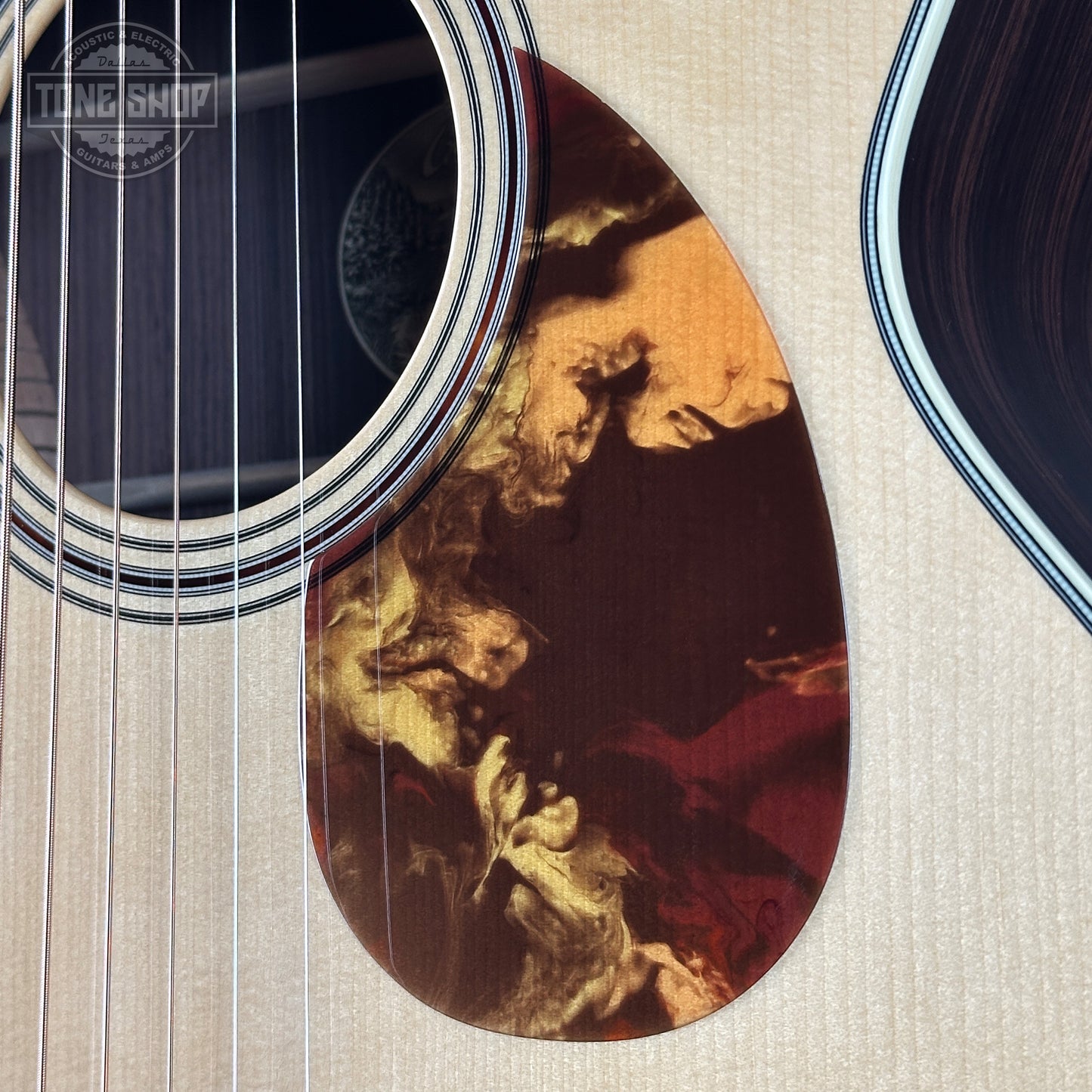 Close-up of an acoustic guitar with a detailed soundhole design on a textured surface.