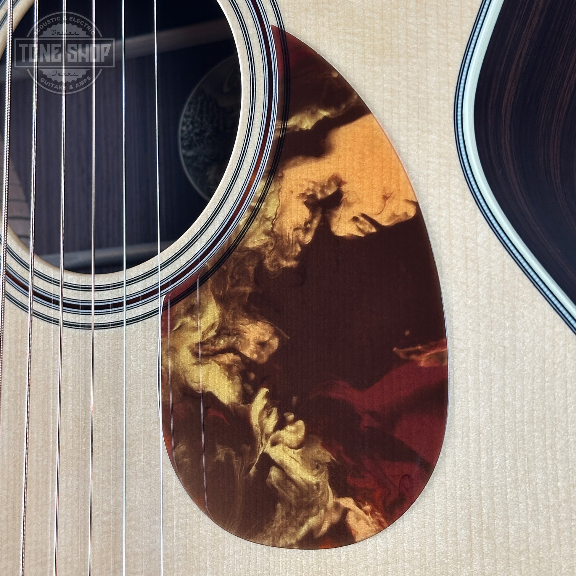 Close-up of an acoustic guitar with a detailed soundhole design on a textured surface.