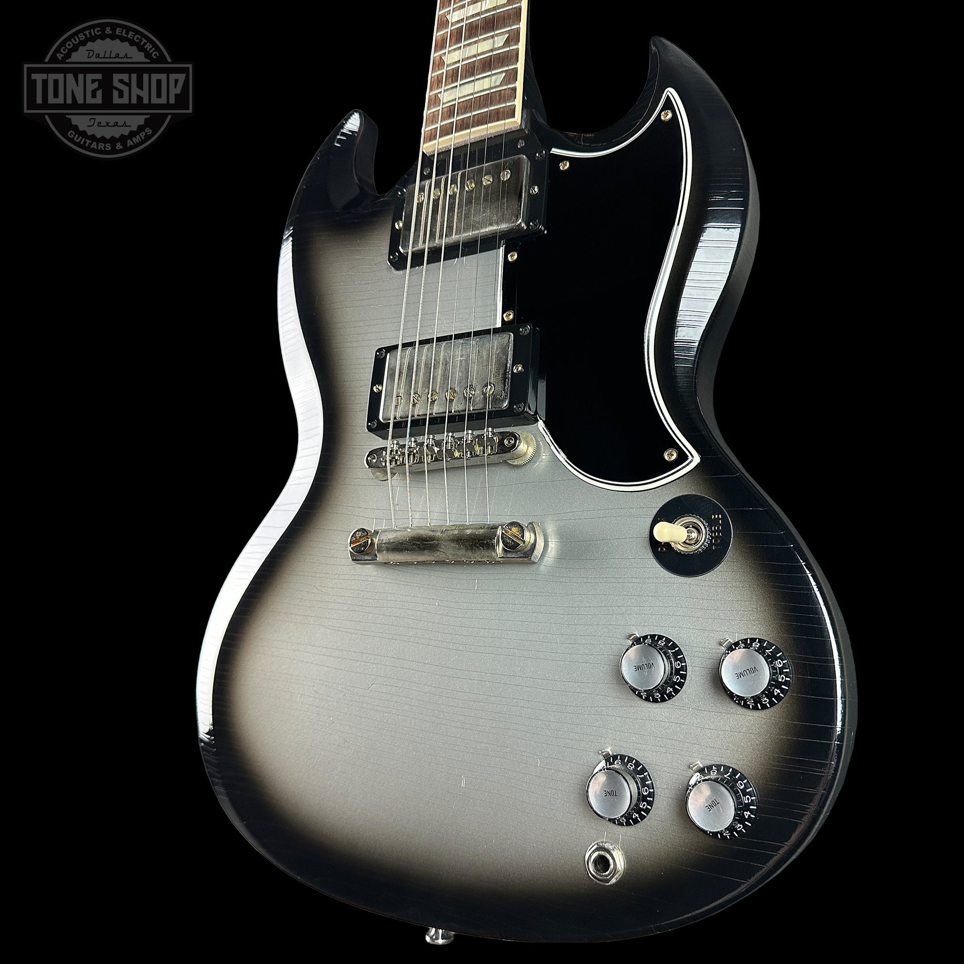 Silver electric guitar with a black background, featuring the 'Tone Shop' logo.