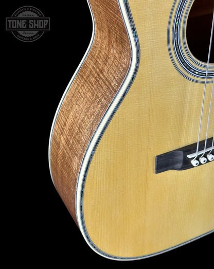 Close-up of a wooden acoustic guitar with a black background and 'Tone Shop' logo.