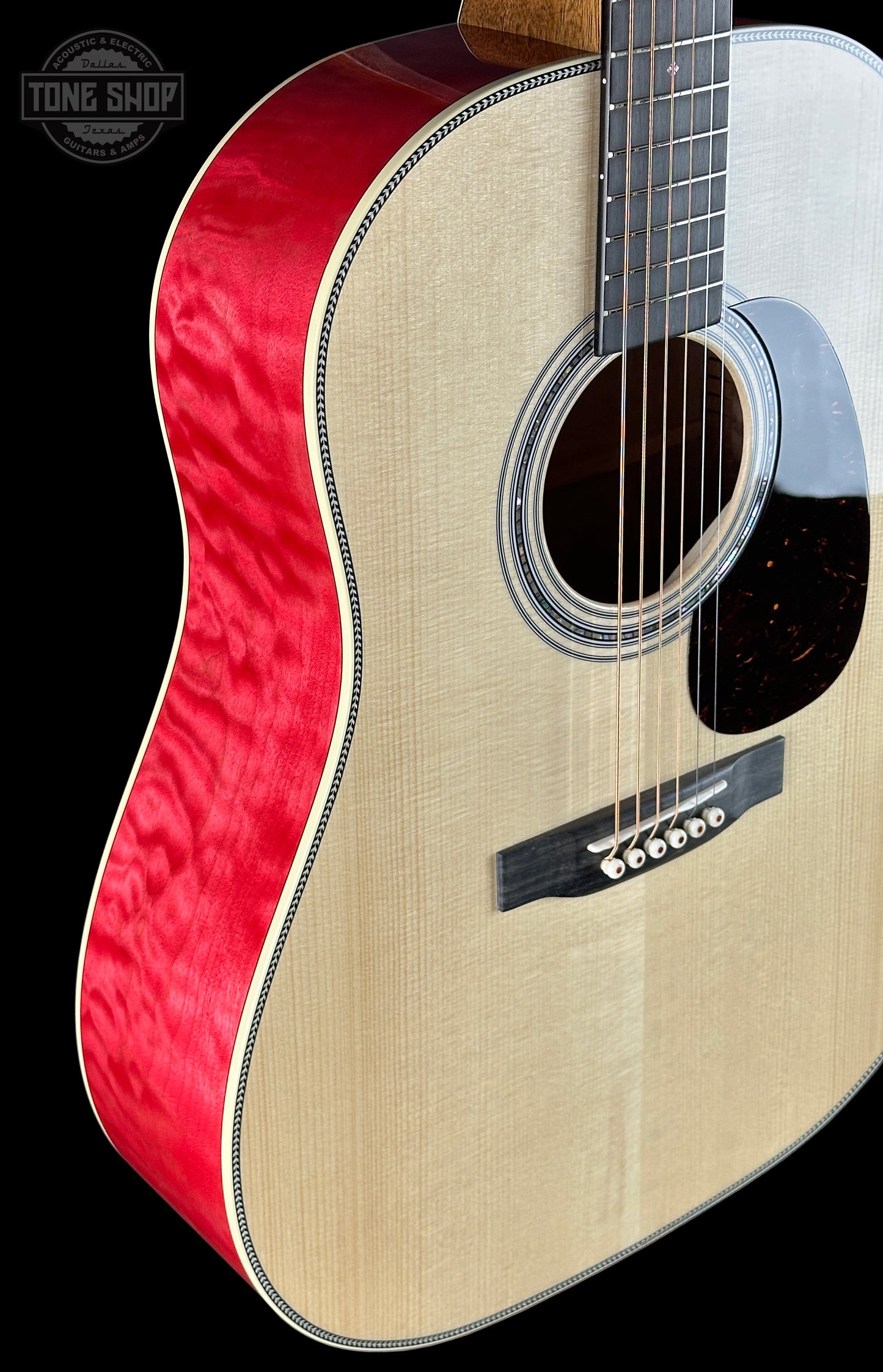 Acoustic guitar with red side and beige body on a black background