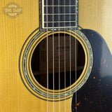 Close-up of an acoustic guitar's soundhole and brand logo in the corner.