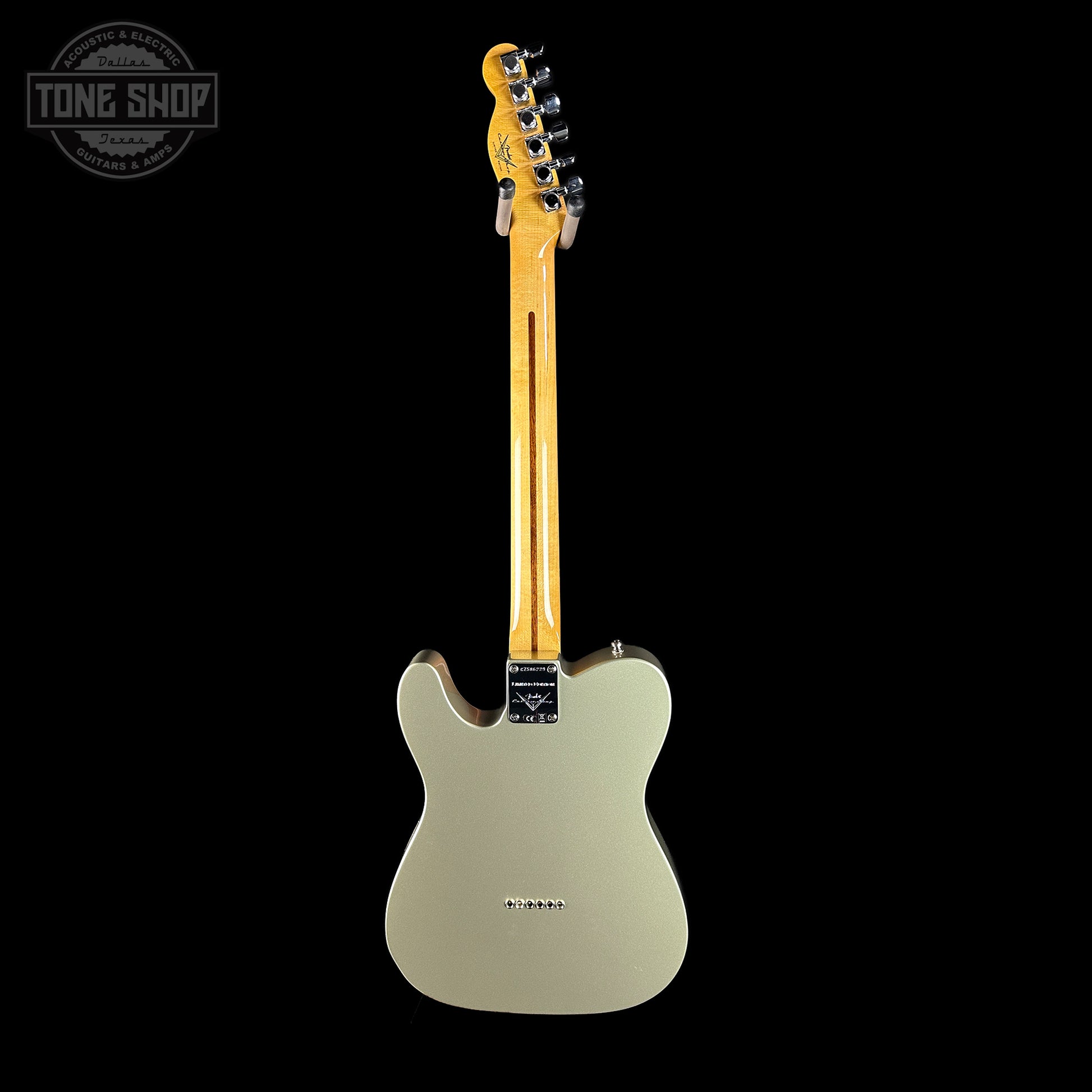 Electric guitar with a gold neck on a black background, featuring the Tone Shop logo.