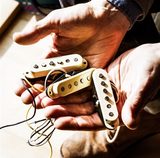 Hands holding Fender Eric Johnson Strat Pickup Set.