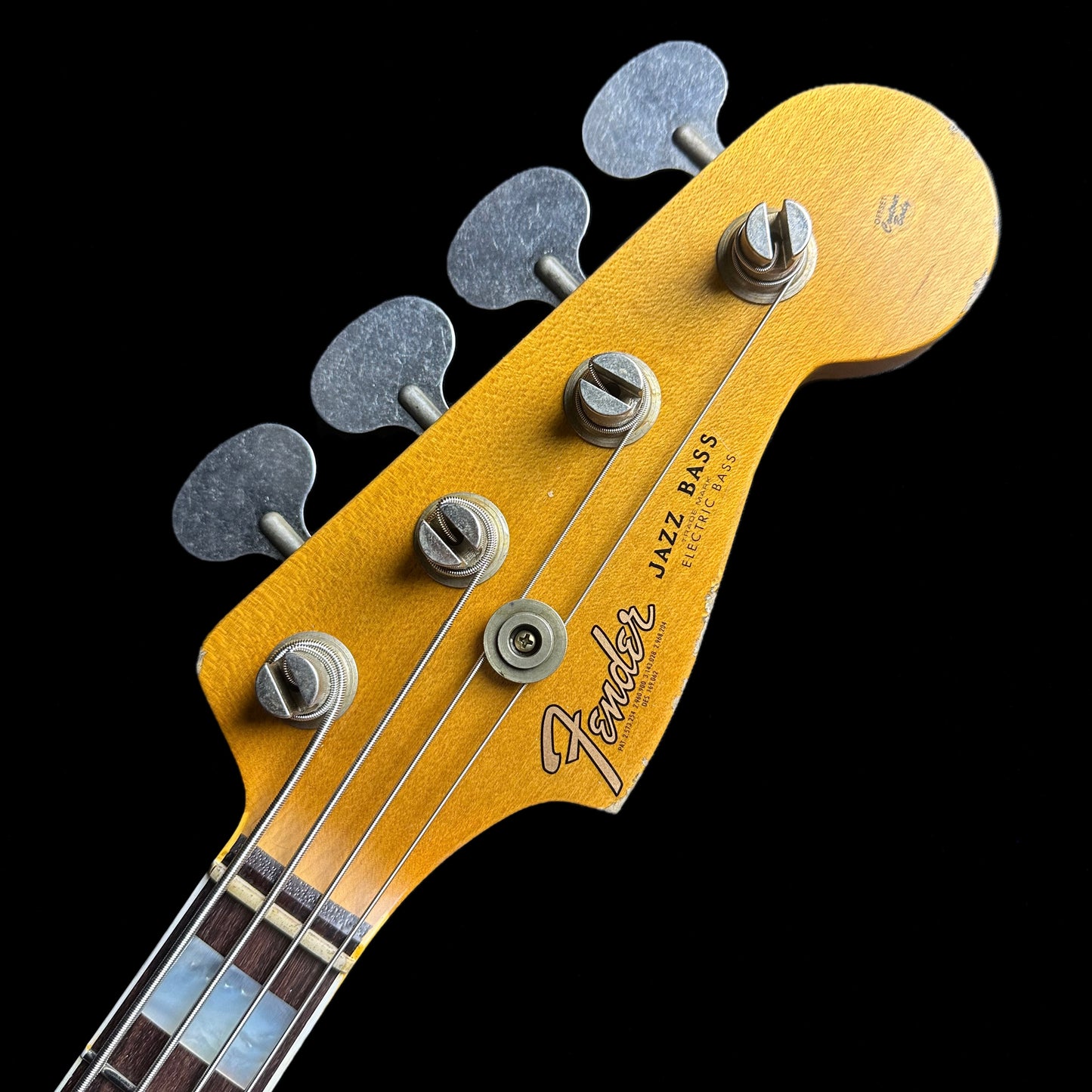 Closeup of Fender Custom Shop Limited Edition Custom Jazz Bass Heavy Relic Aged Black headstock.